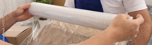 Workers wrapping box in stretch film indoors, closeup. Banner design