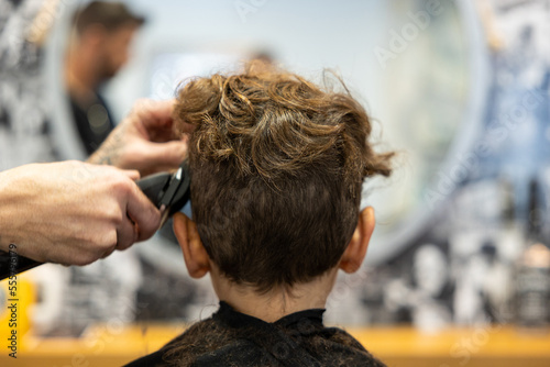 Close up view of a hairdresser cutting the hair of a young boy in a barbershop.