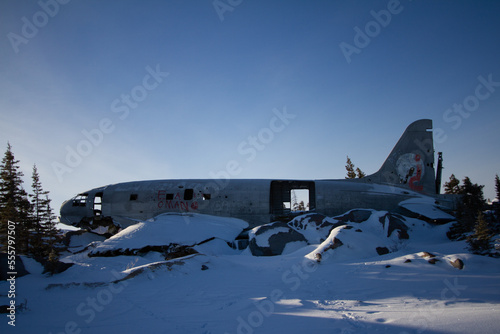 Miss Piggy Plane wreck in Churchill, Manitoba with blue background in frame with snow on rocks in front of crash landing site.