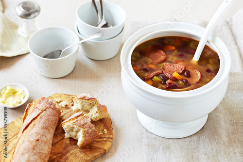 Soup tureen of Hungarian Bean Soup with crusty bread on the side on a linen tablecloth photo