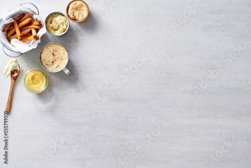 Fries with a variety of homemade mayo condiments for dipping on a grey background