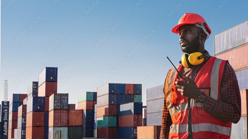 American African engineer or factory worker man using walkie talkie and check up goods at container cargo harbor. American African engineer or factory worker man using walkie talkie and check up goods at container cargo harbor.