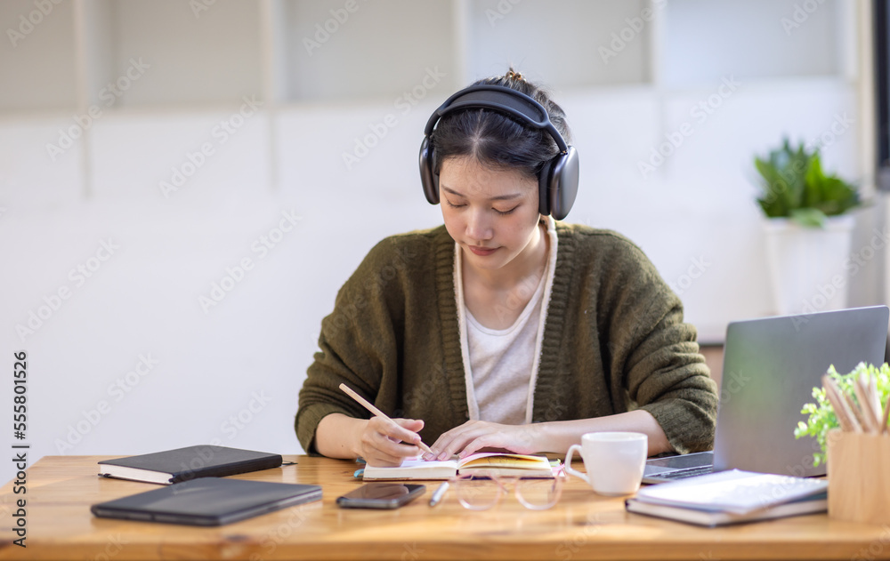 Young adult happy smiling Hispanic Asian girl student wearing headphones talking on online chat meeting using laptop in university campus or at virtual office. College female student learning remotely Young adult happy smiling Hispanic Asian girl student wearing headphones talking on online chat meeting using laptop in university campus or at virtual office. College female student learning remotely
