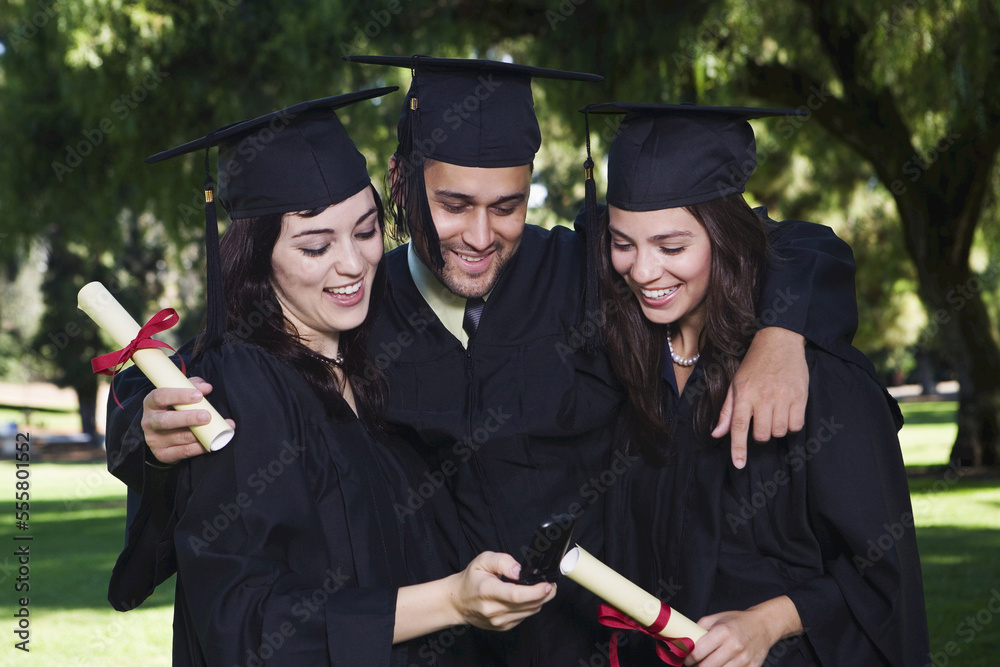 College Graduates Looking at Cellular Phone College Graduates Looking at Cellular Phone