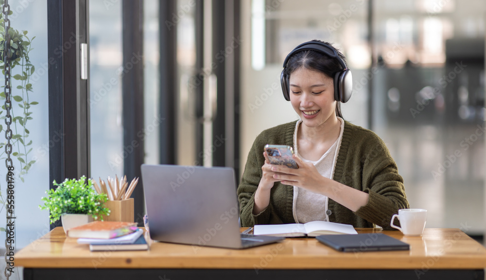 Young adult happy smiling Hispanic Asian girl student wearing headphones talking on online chat meeting using laptop in university campus or at virtual office. College female student learning remotely Young adult happy smiling Hispanic Asian girl student wearing headphones talking on online chat meeting using laptop in university campus or at virtual office. College female student learning remotely