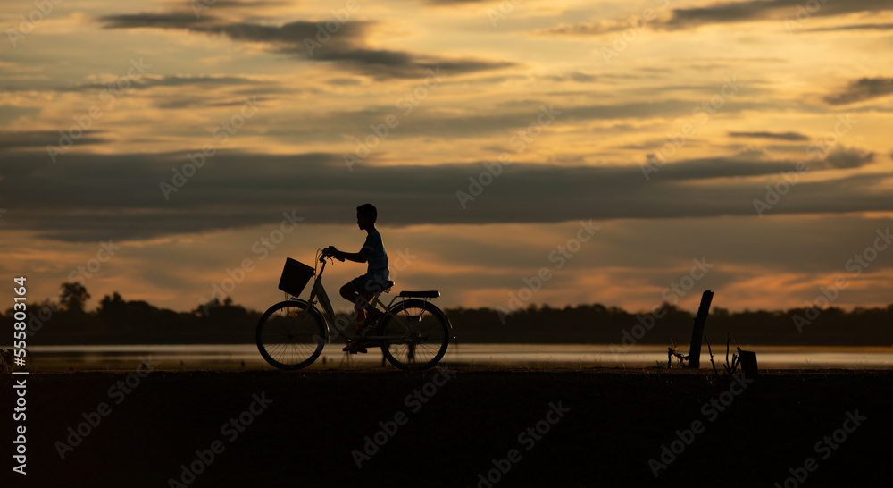 Obraz premium Little boy riding bicycles in the early light of the day as the sun shines