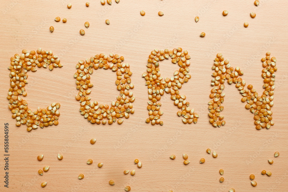 Pile of yellow corn seeds form the word 'CORN' on a brown wooden background, for popcorn. Pile of yellow corn seeds form the word 'CORN' on a brown wooden background, for popcorn.