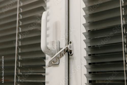 Close-up of double-glazed plastic window frame, one-way kitchen window handle, PVC window latch securing sash, metal shutters. The concept of repairing doors and windows in the house