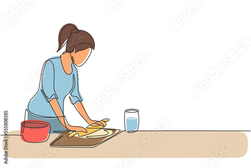 Single one line drawing young woman making cookie dough using rolling pin at kitchen table. Making bakery and homemade pizza at home. Modern continuous line draw design graphic vector illustration