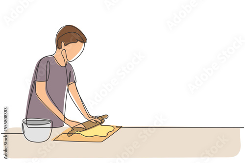 Single continuous line drawing young man making cookie dough using rolling pin at cozy kitchen table. Making bakery and homemade pizza at home. Dynamic one line draw graphic design vector illustration