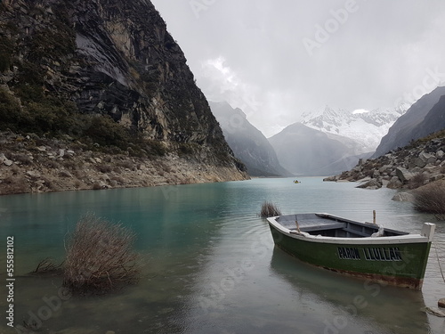 Boat in a mountain lake. Very blue and clear water, with raindrops in it. Mountains with snow on the background.