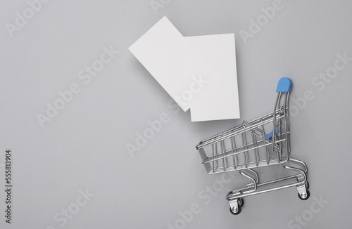 Mini shopping cart with business cards on a gray background