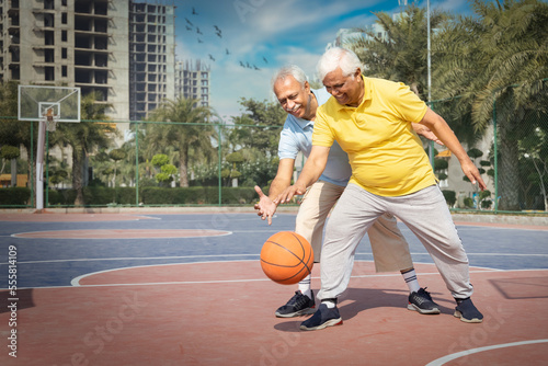 Two seniors on the basketball field playing basket.