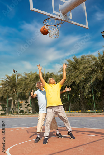 Two seniors on the basketball field playing basket. © G-images