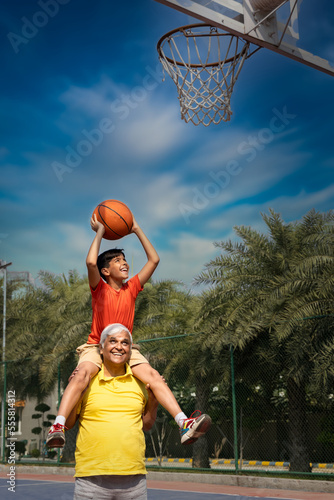 Grandfather and his grandson enjoying and playing together on basketball court. © G-images