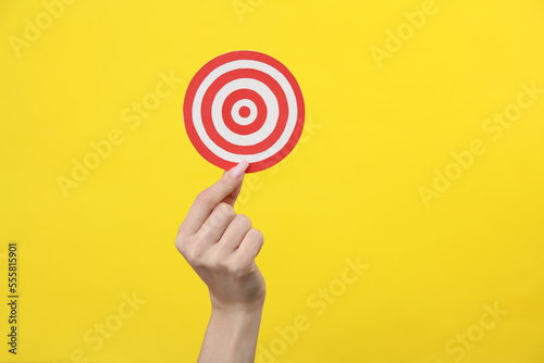 Hand holding a target on a yellow background. Business concept