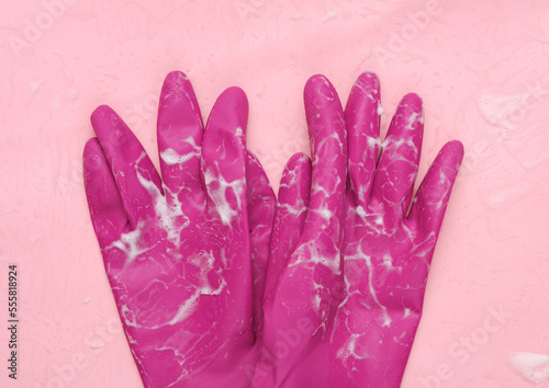 Rubber gloves with foam on a pink background. Cleaning concept