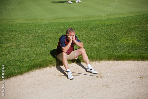 Man Sitting by Sand Trap on Golf Course photo