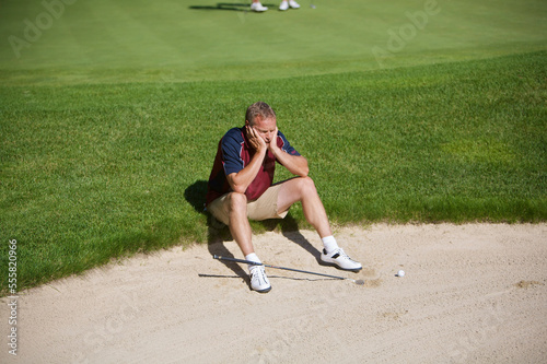 Man Sitting by Sand Trap on Golf Course