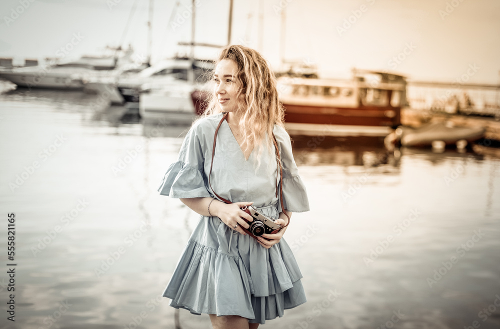 Portrait of a cute female tourist with a camera on the background of the yacht club Portrait of a cute female tourist with a camera on the background of the yacht club