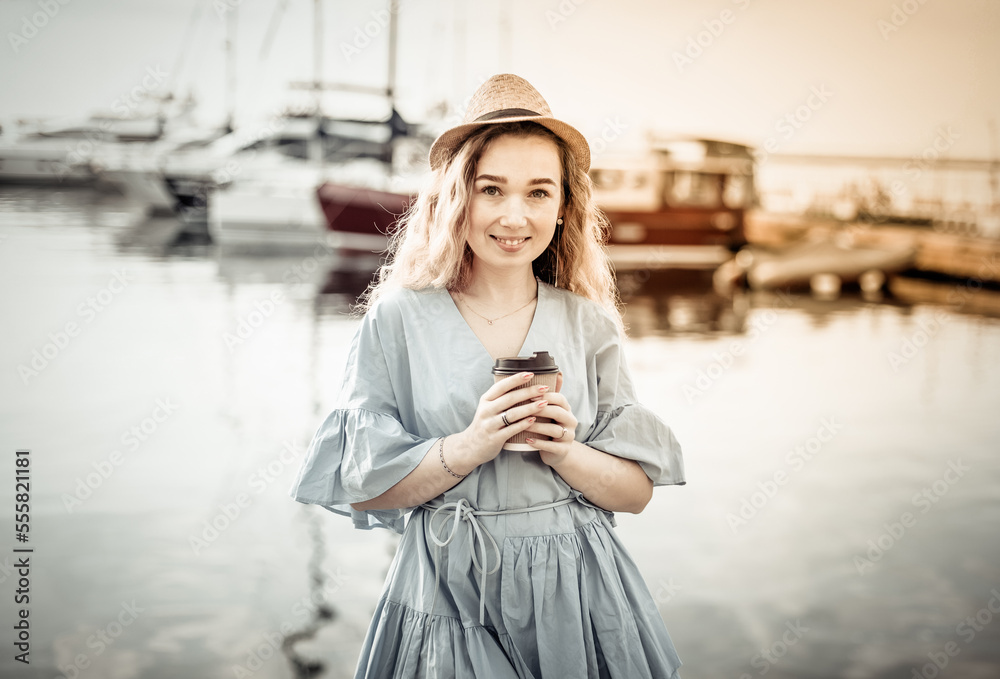 Portrait of cute woman with cup of coffee on the background of yacht club