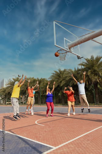 Family playing basketball together at basketball court. © G-images