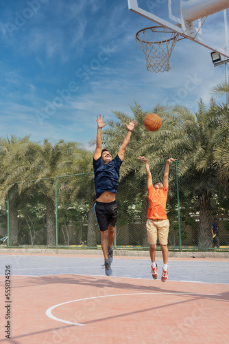 Father and son playing basketball at basketball court. © G-images