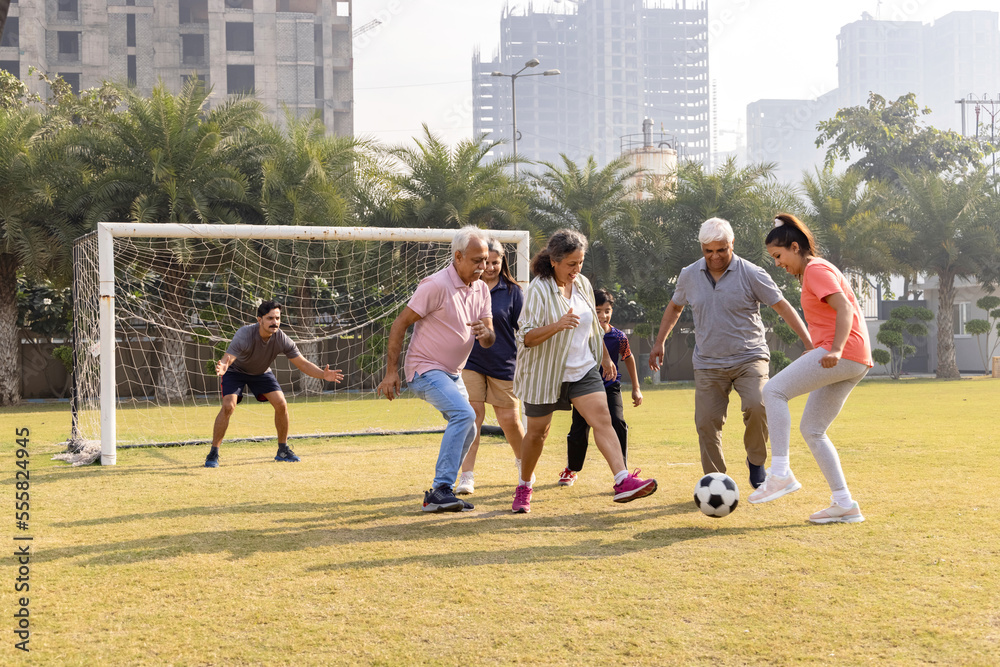 Obraz premium Happy multi generation family playing football together in the football ground.