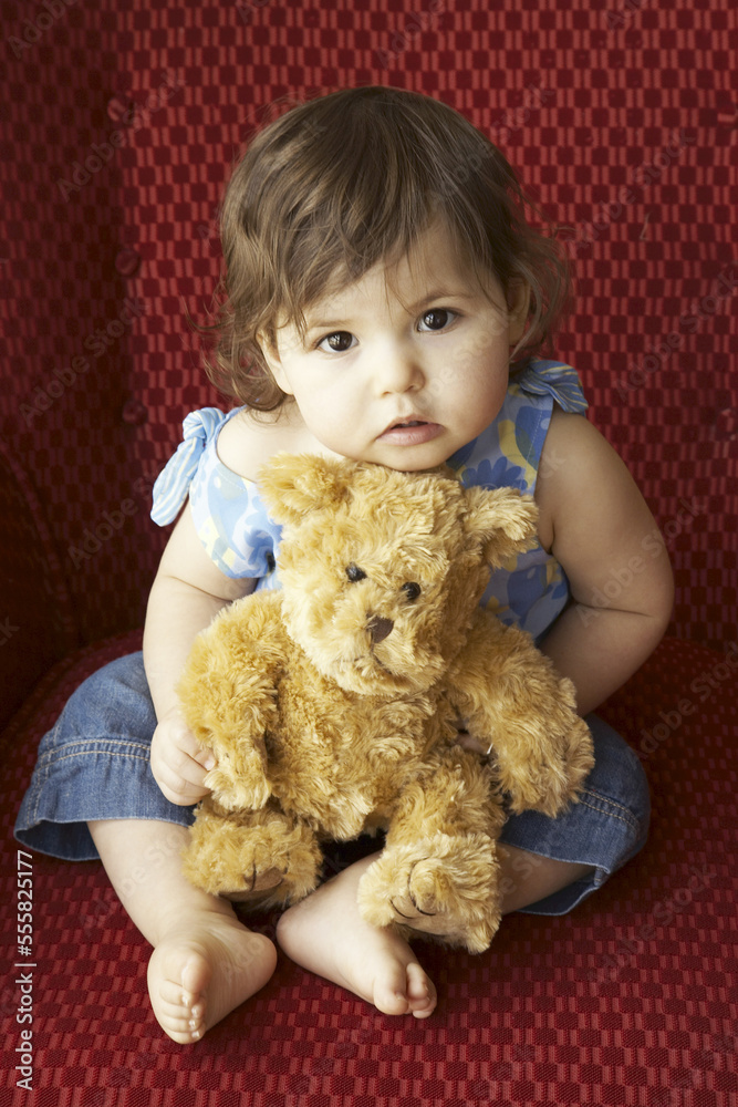 Little Girl Sitting on Chair with Teddy Bear Stock Photo | Adobe Stock