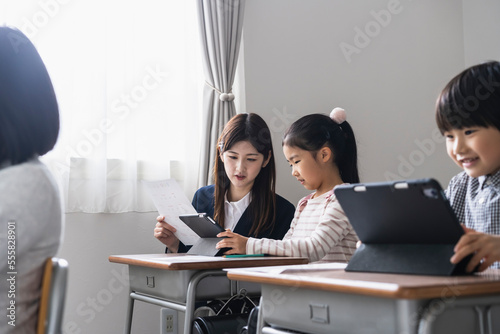 タブレットPCを使った授業をする日本人小学生と女性教師