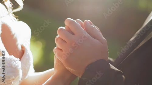 A couple in love tenderly holding hands against the background of sunlight. Close-up shooting of hands