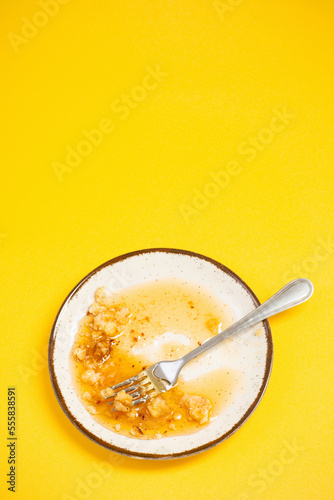 dirty plate with honey and pie crumbs on yellow background