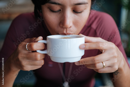 A young female cyclist having a cup of coffee at a cafe by the mountains.