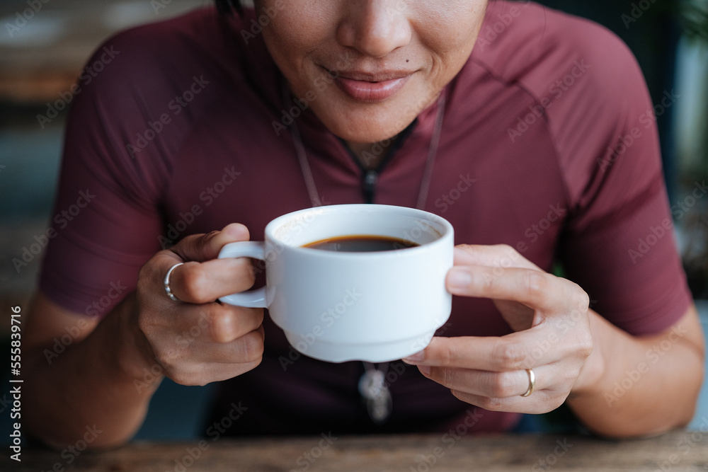 A young female cyclist having a cup of coffee at a cafe by the mountains. A young female cyclist having a cup of coffee at a cafe by the mountains.