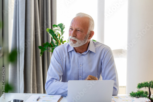 Financial advisor businessman using his laptop and doing some paperwork while sitting at desk and working.