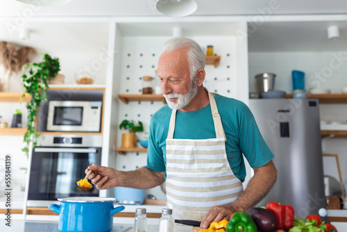 Photo Happy senior man having fun cooking at home - Elderly person preparing health lu