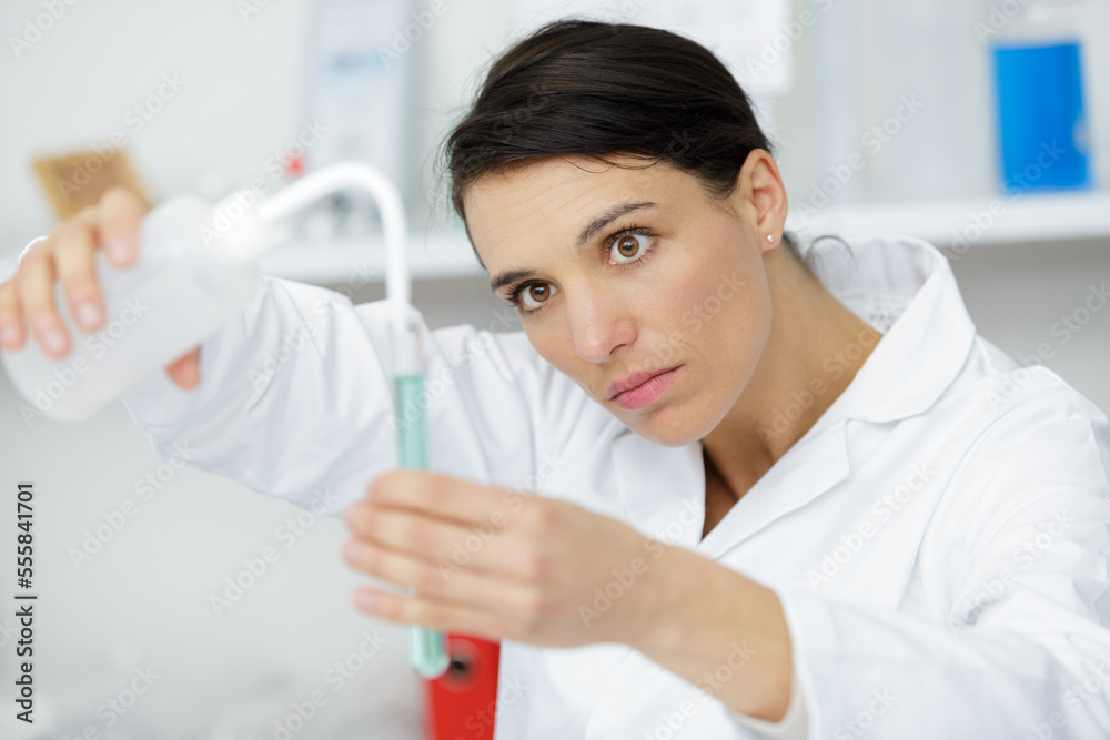 young attractive female scientist dripping a substance into test tube young attractive female scientist dripping a substance into test tube