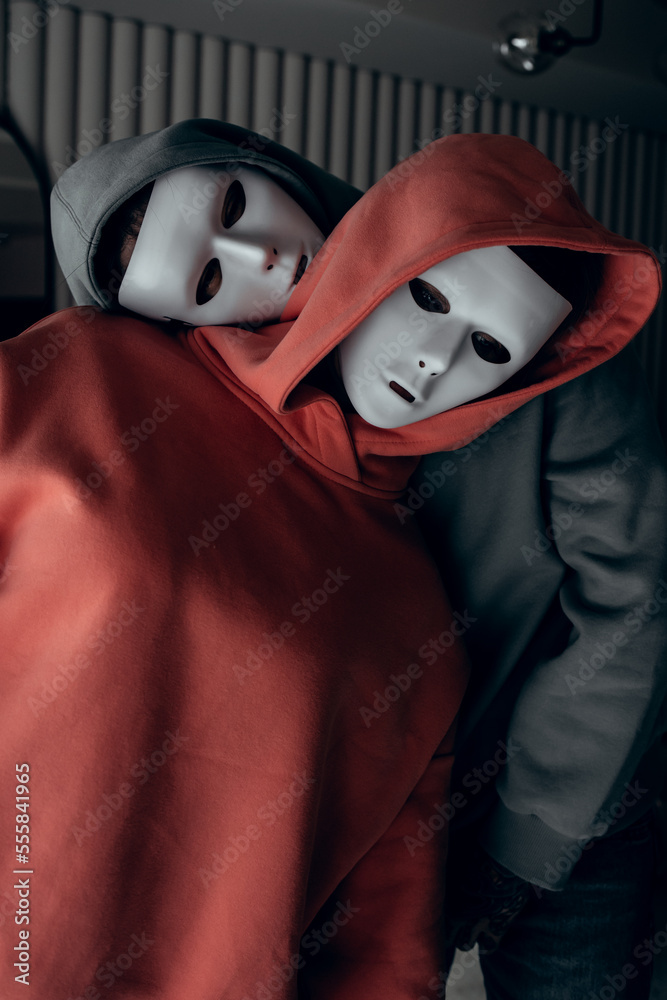Portrait of two people in white theatrical masks and hood on black background. Concept of mental disorders, human roles. High quality photo - obrazy, fototapety, plakaty 