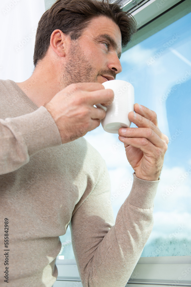 thoughtful businessman drinking coffee looking through window thoughtful businessman drinking coffee looking through window