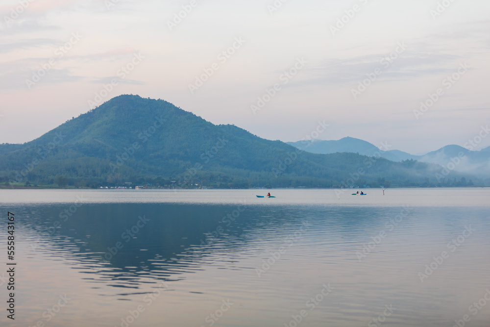 Sunrise time at lake or river with small kayak boat with mountain on the background.