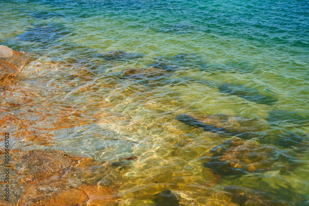 Transparent sea water through which you can see the bottom of the rocky shore