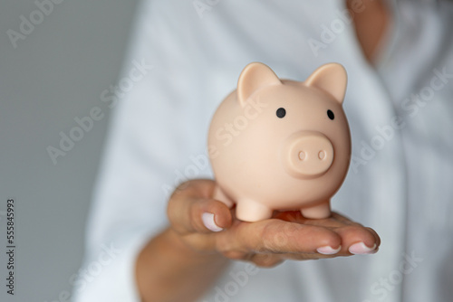 female hands puts a coin in a pink piggy bank. The concept of saving money or savings, investment