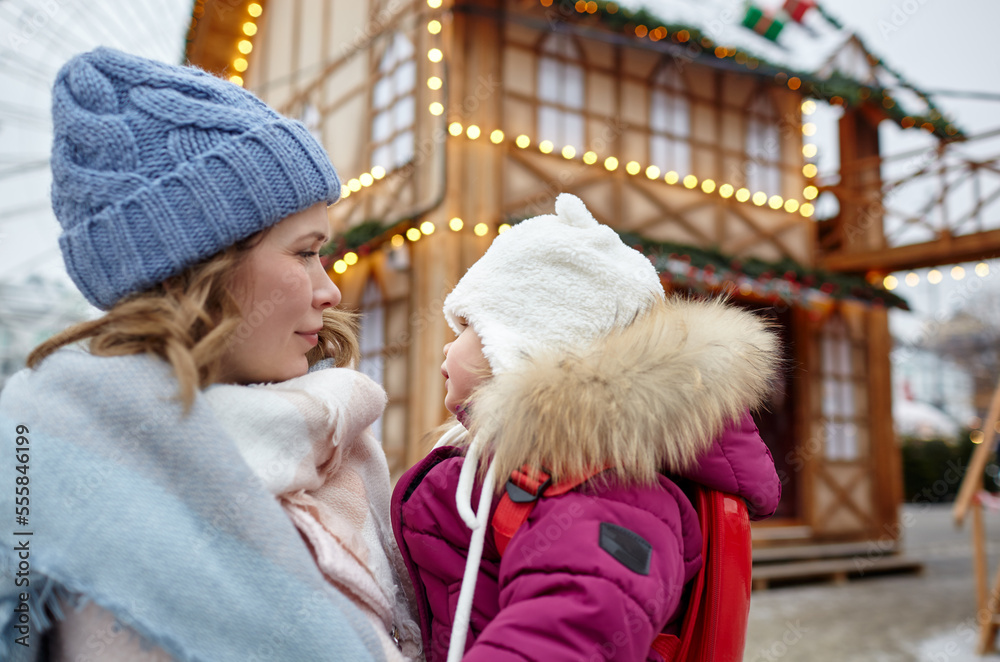 Mother and daughter are walking around the city on Christmas and New Year holidays. Parent and little child having fun outdoors Mother and daughter are walking around the city on Christmas and New Year holidays. Parent and little child having fun outdoors
