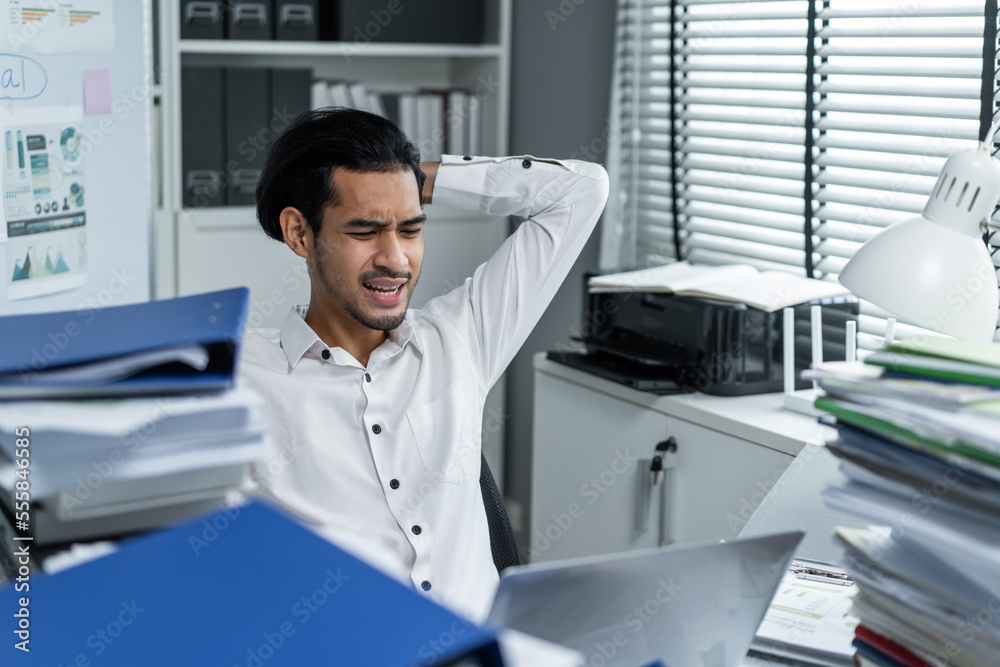 Exhausted Asian young businessman worker working on table in office. 