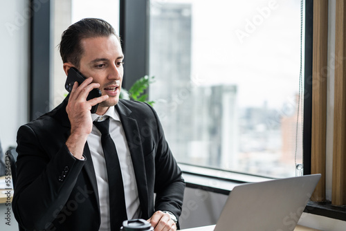 Caucasian young businessman talking on smartphone and working in office. 