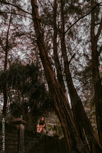 A girl walks under palm trees. Dark photo processing