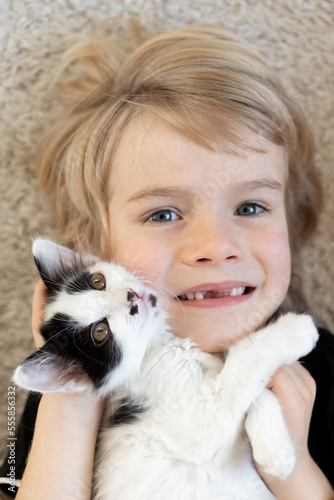 face of contented blond boy and black and white kitten. Top view, selective focus. Pets. Happy childhood. Lifestyle. care and joy from animals