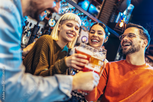 Smiling young friends drinking craft beer in pub