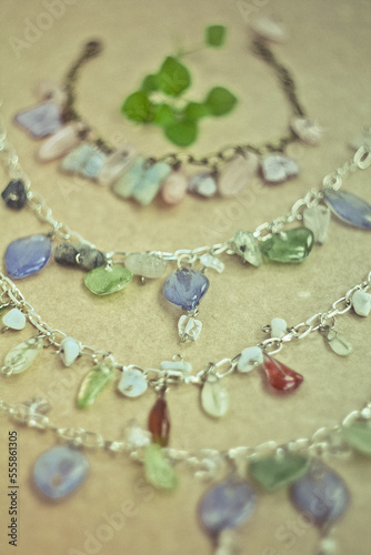 Close up bracelets with gemstones and silver chains concept photo. Side view photography with plywood on background. High quality picture for wallpaper, travel blog, magazine, article