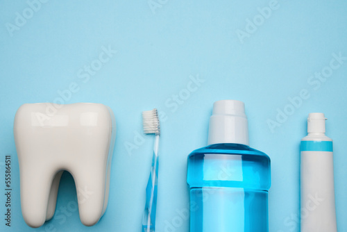 A toothbrush with toothpaste and oral rinse on blue background